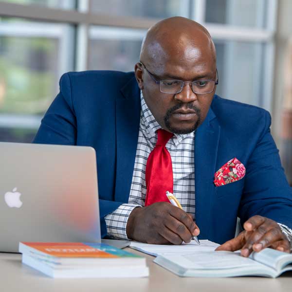 Doctoral taking notes at a laptop